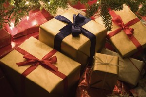 Christmas presents piled underneath a christmas tree.