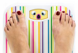 32693293 - feet on bathroom scale with crying cute face on dial